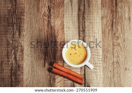 natural coffee in a small cup On wooden background . next to a cup of organic coffee, lie two cinnamon sticks