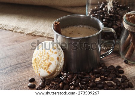 Coffee in a metal cup standing on a wooden table  in the coffee beans