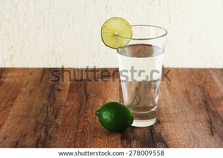 Clean water is standing on a wooden table. Next to a glass of water is lime. Clean water is standing on a wooden table. Next to a glass of water is lime. Healthy lifestyle concept