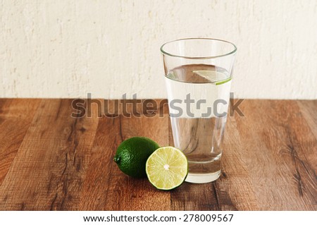Clean water is standing on a wooden table. Next to a glass of water is lime. Clean water is standing on a wooden table. Next to a glass of water is lime. Healthy lifestyle concept