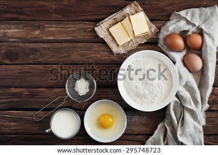 ingredients for making pancakes or cake - flour, egg, butter, milk on  the old wooden background. top view. rustic or rural style. background with free text space.  Ingredients for the dough