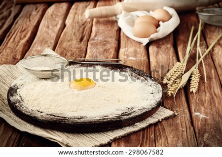 Egg yolk in flour close up on a wooden table. Rural or rustic style. Copy space. Free space for text. Toned vintage style