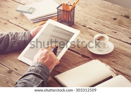 Men hand clicks on the screen blank tablet computer. concept man working from home using tablet computer or working outside the office. Free space for text. Closeup. Top view. Toned in vintage style