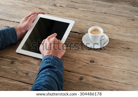 a men presses the blank screen tablet computer for wooden office desk. Concept man working from home using tablet computer. Free space for text. Top view. Copy space