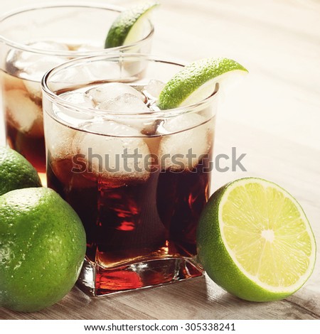 Cocktail with cola, ice and lime on a wooden table. Summer cocktail. Copy space. Free space for text. Closeup