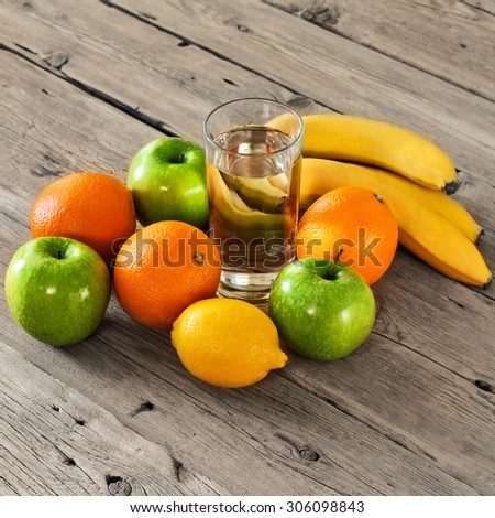 fruit with a glass of water on a wooden table. Orange, apple, banana, lemon. Top view. closeup. Free space for text. Square frame