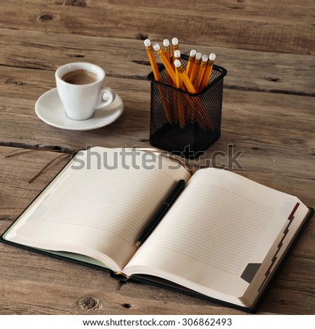 blank notebook on wooden table with a cup of black coffee and pencils. Closeup. View from above. Copy space. Free space for text. Square frame