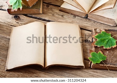 Vintage books. Open blank book on wooden desk with autumn maple leaves close up. Copy space. Free space for test