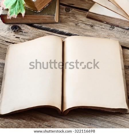 Vintage books. Open blank book on wooden desk with autumn maple leaves close up. Copy space. Free space for test. Square frame