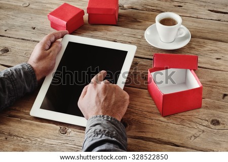 man orders Christmas gifts using a tablet computer via the Internet. Man\'s hand clicks on a blank screen tablet computer