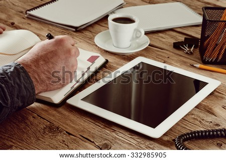 The man working at the office. White tablet on a wooden office desk closeup. Top view. Copy space.