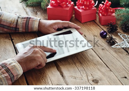 Man buys Christmas gifts through the Internet using a tablet computer. The man clicks on tablet computer screen closeup. Free space for text