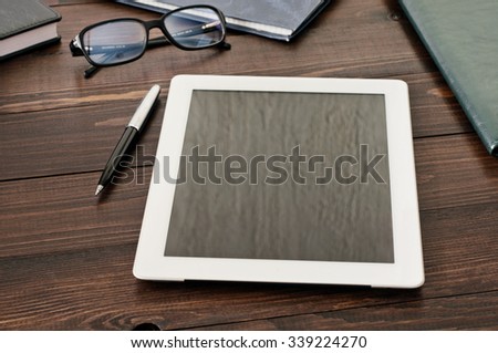 On the office desk is a tablet computer, a noteboo Top view a leather folder and glasses. Top view. Copy space. Free space for text. Workplace