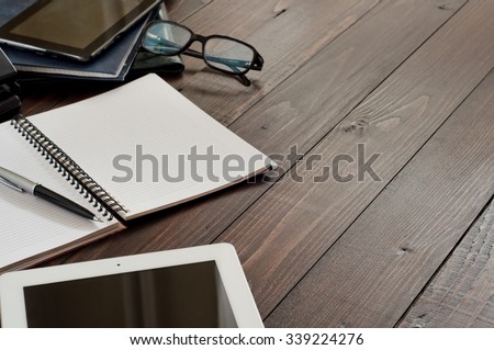 Office workplace. Open notebook, tablet computer, glasses, ballpoint and leather business folders on the office table. Top view. Free space for text. Copy space.