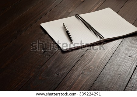Open notepad with a pen on a brown wooden office desk. Copy space. Free space for text