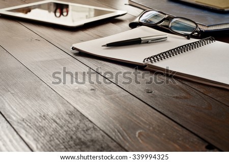 Open notebook, tablet computer, glasses and folders on the office table. Top view with copy space. Free space for text. Office workplace