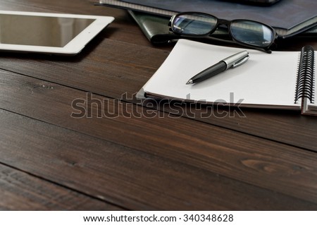 Open notebook, tablet computer, glasses and folders on the office table. Copy space. Free space for text. Top view