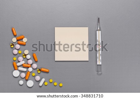 On a gray table paper for notes with a pills, capsules and thermometer . Top view. Copy space