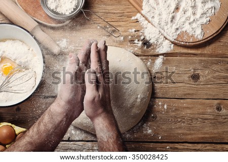 Male baker prepares bread. Male baker slaps on dough. Making  bread. Top view. Rustic style