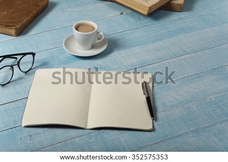 Home office table with open notebook with blank pages, a cup of espresso coffee and books. Top view with copy space