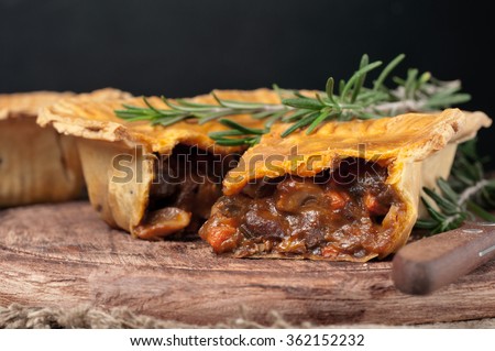 Fresh australian meat pie on the wooden table closeup with copy space, rustic style