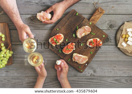 Couple clinking glasses with white wine, top view