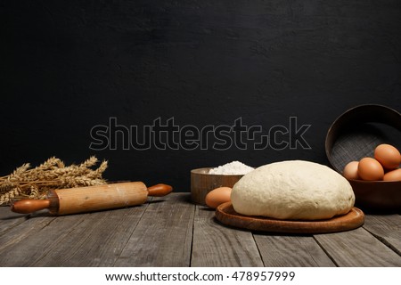 Dough on wooden table on dark background with space for an object in a bakery