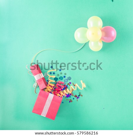 Red gift box with various party items and balloons. Celebration background. Top view