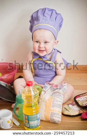 Baby wearing chief hat playing with kitchen tools