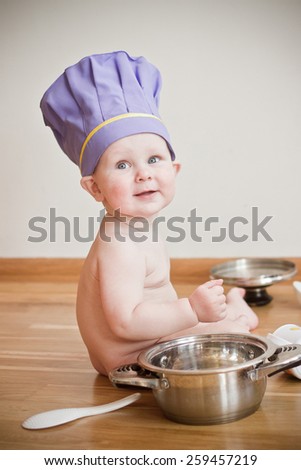 Baby wearing chief hat playing with kitchen tools