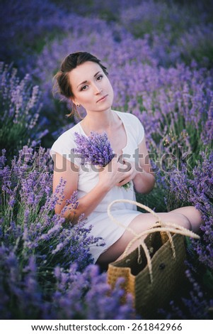 Beautiful young woman in a white dress posing in a lavender field