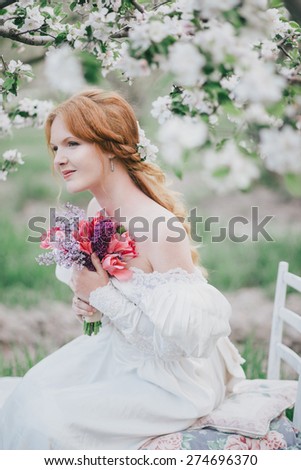 Beautiful bride in a vintage wedding dress posing in a blooming apple garden. Spring mood. Young woman in a white vintage dress