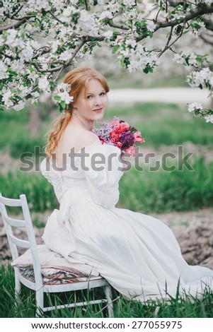 Beautiful bride in a vintage wedding dress posing in a blooming apple garden. Spring mood. Young woman in a white vintage dress