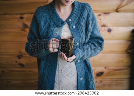 Woman sitting in a wicker chair on a cozy balcony with a cup of tea
