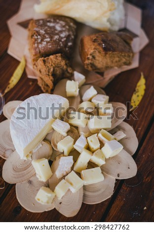 Two glasses of white wine with cheese and bread on a wooden table