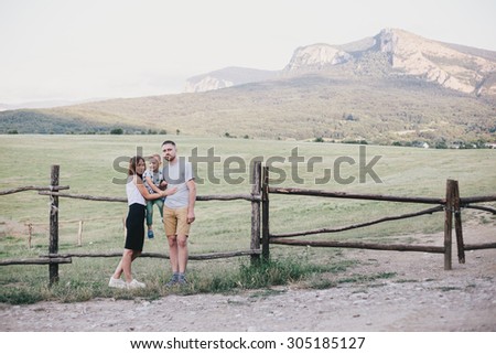 Happy family - mother, father and son - relaxing at a countryside with mountains and lake