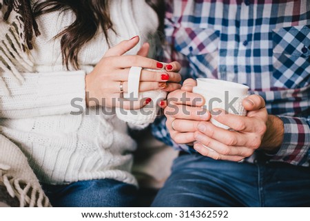 Young couple's hands with two cups of hot tea