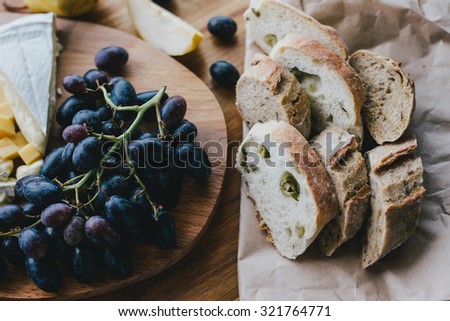 Table with wine, cheese, bread, grapes and pears standing on a cozy balcony