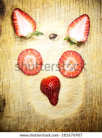 animal\'s face from strawberry on a wooden board