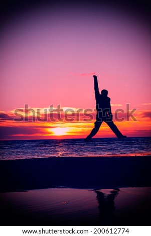 happy man jump on a beach at sunset