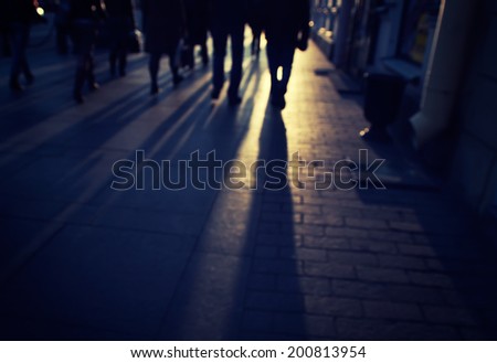 silhouettes of people on the cobblestone pavement at sunset