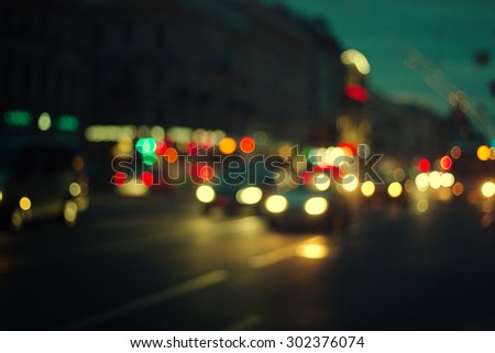 defocused night city life: cars, people and street lamps