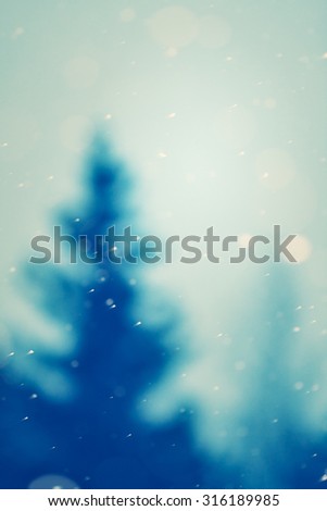 christmas snowfall and blurred christmas tree on background in the evening, natural photography