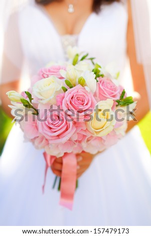Bride in wedding dress holding a roses bridal bouquet.