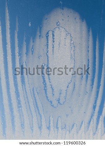 Weird shape of water and frozen snow on glass window, condensation and melting ice on transparent glass of window in winter in contact with morning warm sunlight. Vertical orientation, nobody.