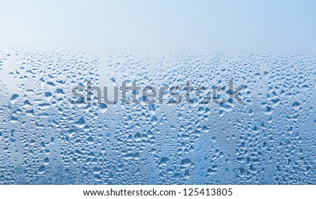 Condensation drops on glass zoom abstract, transparent glass of window, wet textured blue tone background. Horizontal orientation, nobody