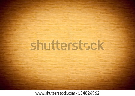 Orange tone texture material abstract, bright in central part with dark vignette on the borders background, blank cloth surface in horizontal orientation, nobody.