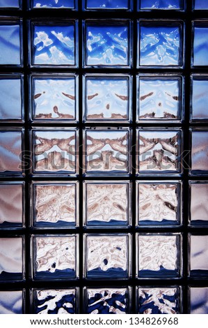 Blue toned glass brick window abstract with dark vignette, transparent glass blocks surface background in horizontal orientation, nobody.
