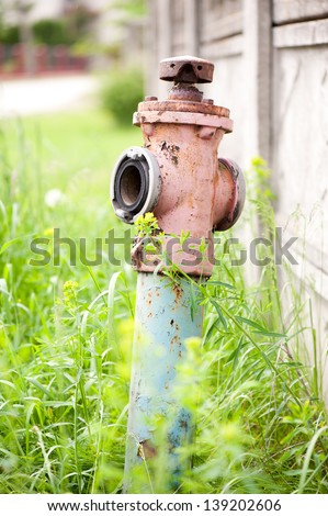 Single old rusted hydrant standing in grass, obsolete object in vertical orientation, open air in Poland, nobody.
