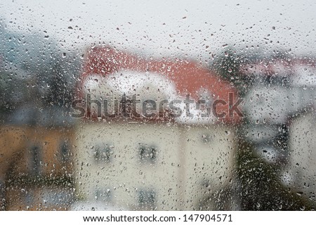 Rain flow on window glass home blurred abstract, many raindrops on transparent glass of window and neighbour house visible through wet glass. Horizontal orientation, nobody.